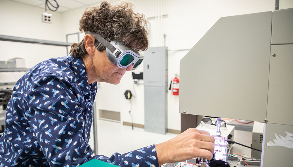 Dr. Christi Madsen wearing safety goggles while working with lab equipment in the Solar Optics Academic Teaching Labs and Testing Facility