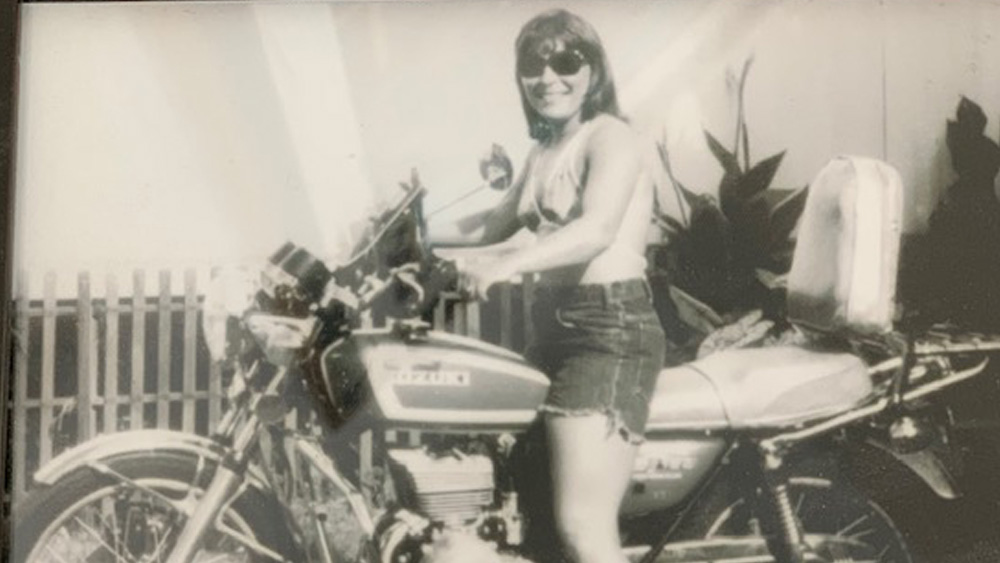 A black and white photo of a young Bonnie Hunt on a motorcycle.