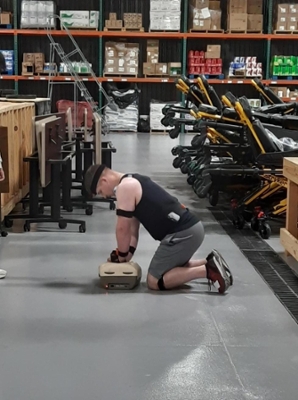 A man kneels next to a dummy, practicing CPR.