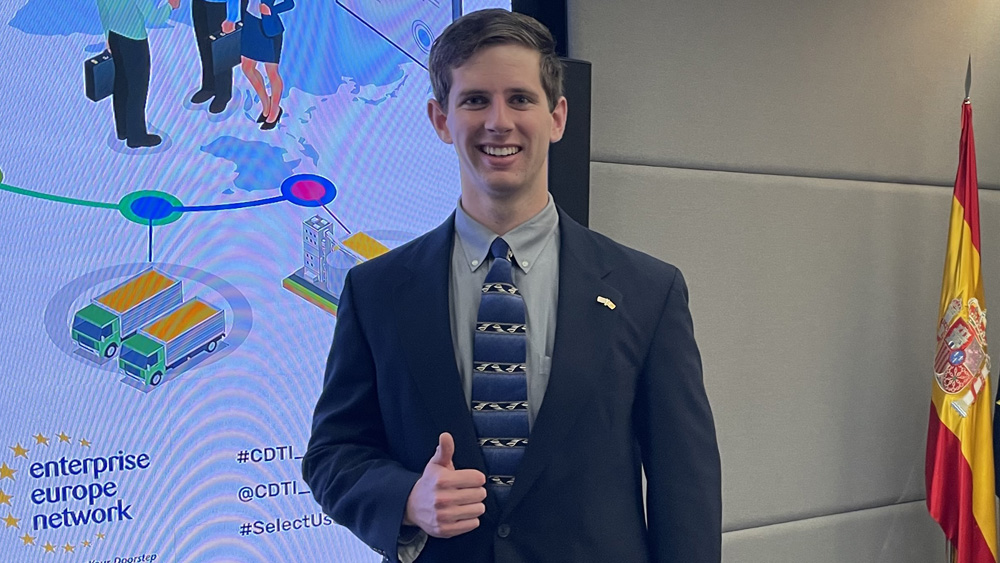 Austin Kees stands in front of a PowerPoint screen, giving a thumbs up to the camera.