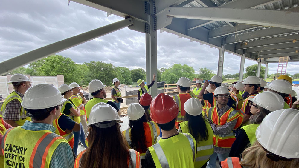 A group of students in hard hats and vests get a lesson from a faculty member. 