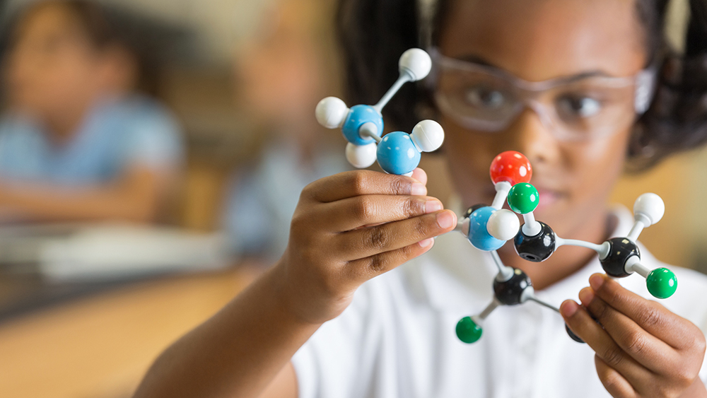 Young girl in safety goggles playing with a science project of molecules.  