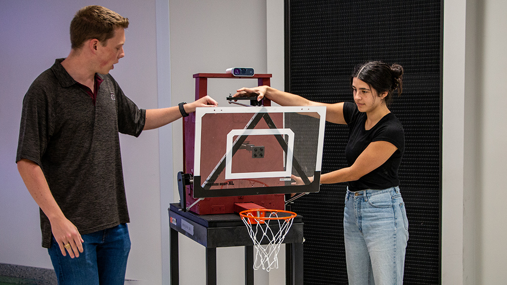 Two students demonstrating how the hoop and backboard system can move in response to inputs from the motion-tracking camera. 