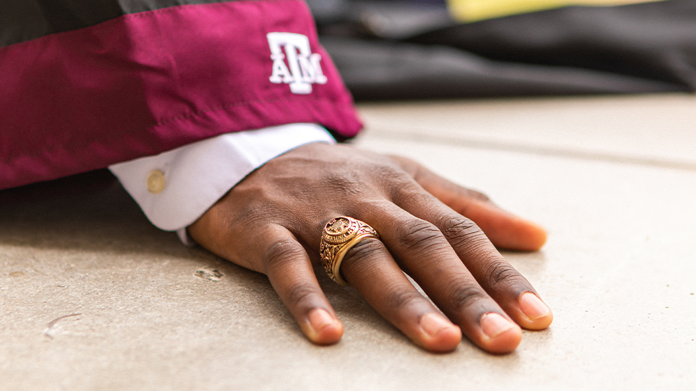 Aggie ring and Texas A&M logo on a graduation robe cuff.