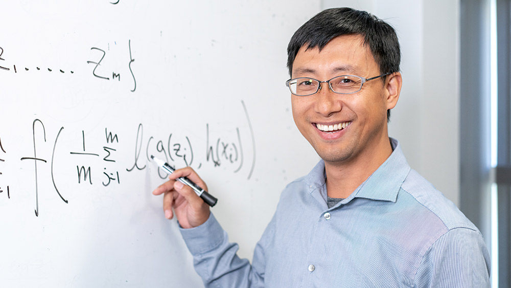 Dr. Tianbo Yang standing next to a whiteboard
