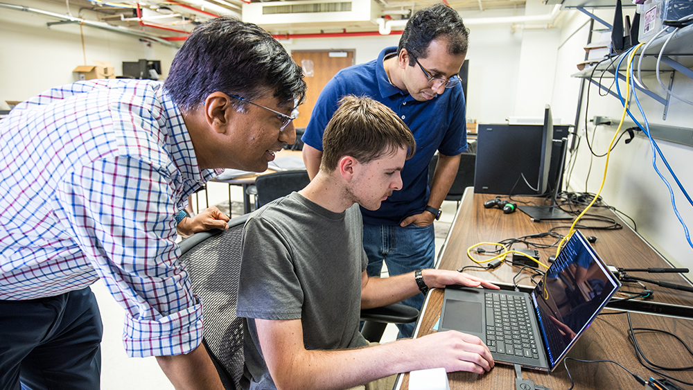 Image Professors Shakkottai and Kalathil looking over a student's shoulder at software-defined radio.