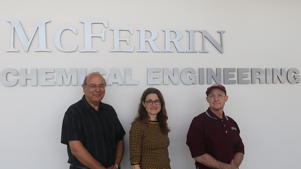 Starting from the left Drs. Dimitris Lagoudas, Jodie Lutkenhaus and James Boyd standing in front of the sign Artie McFerrin Department of Chemical Engineering. 