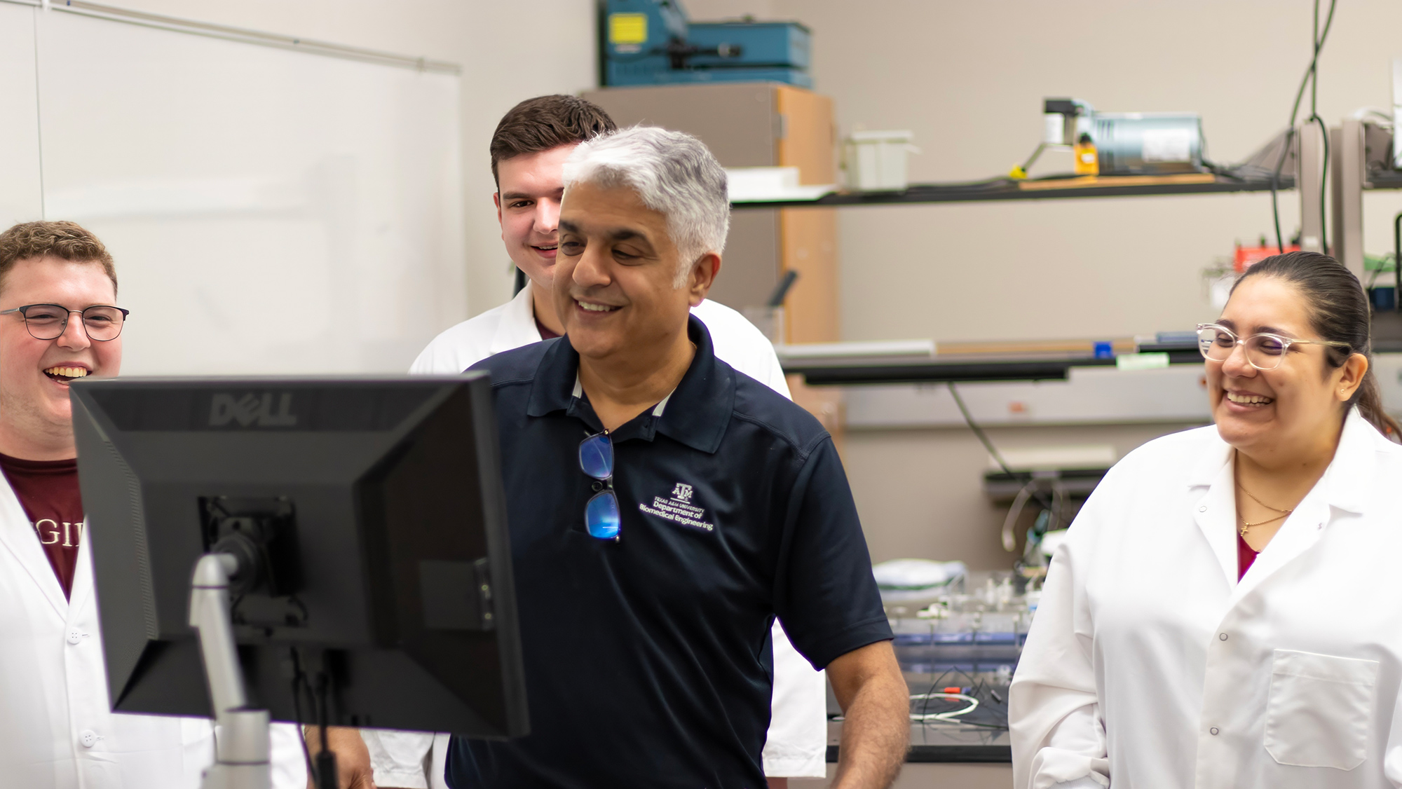 Dr. Balakrishna Haridas using a simulator to test out a pediatric device with his student lab personnel watching behind him.