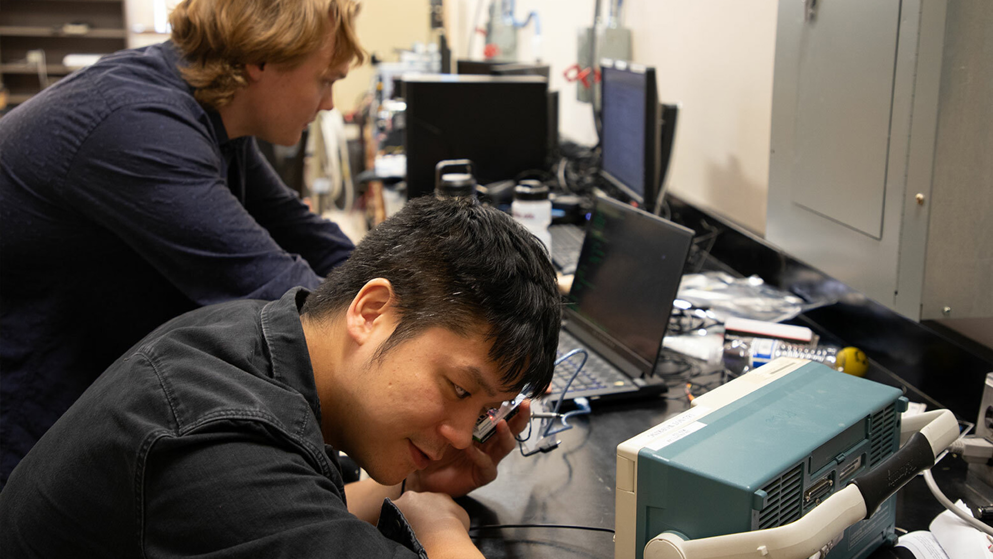 Peng-Hao Huang and Nicholas Heinrich-Barna working on hardware in a lab.
