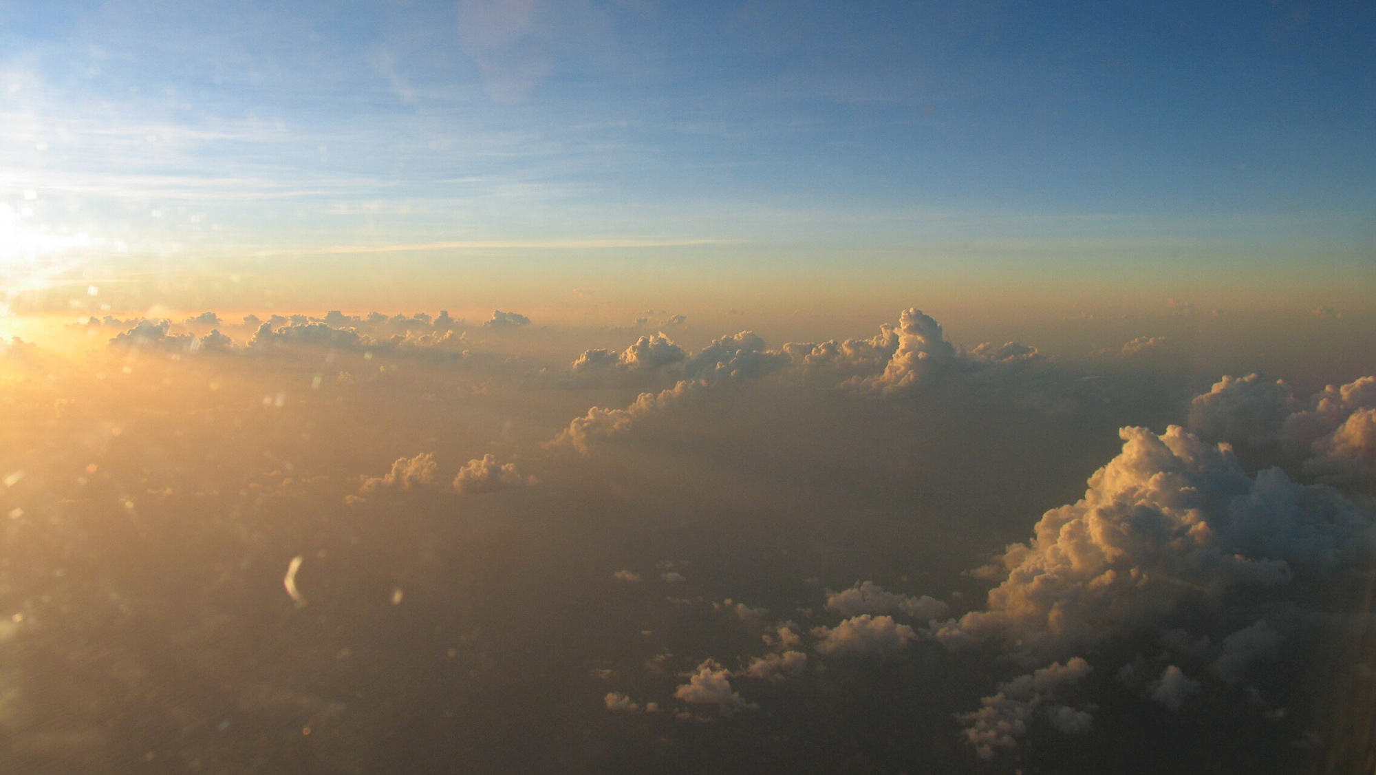 A photo of an air layer and dust-filled clouds, taken at elevation and facing the sun on the horizon.