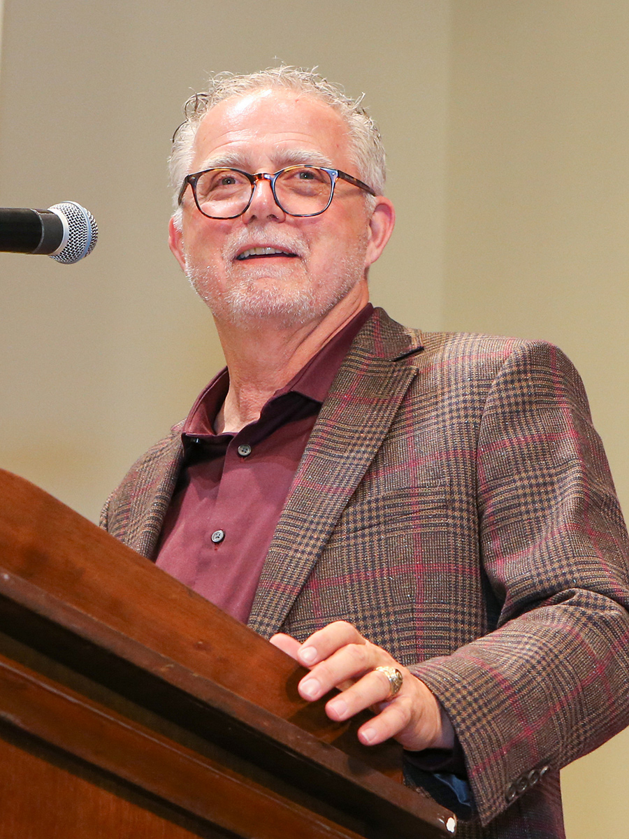 Man standing at a podium with a microphone.