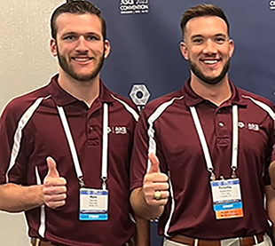 Two men posing with their thumbs up.