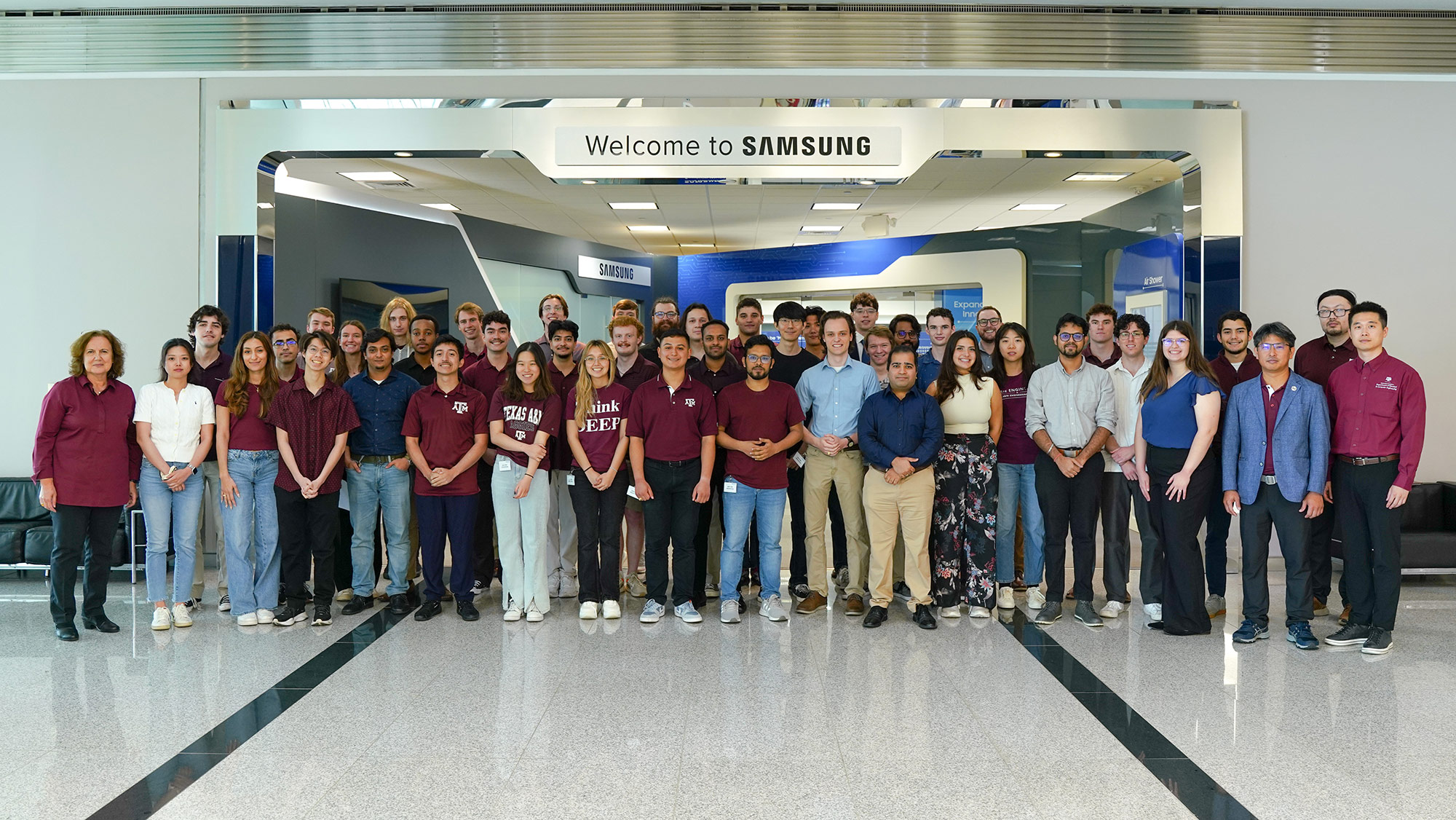 A group of people stand in front of a sign that reads, “Welcome to Samsung.”