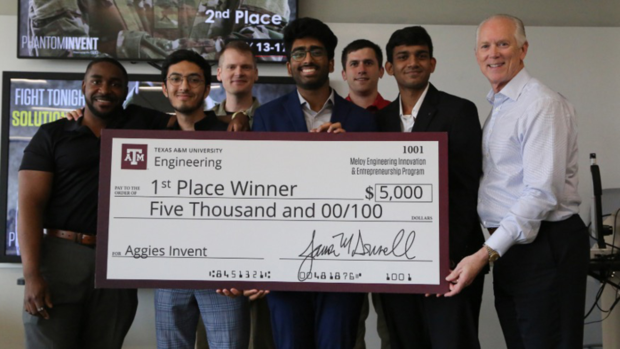 Students holding a large check for $5,000 that says first place winner.