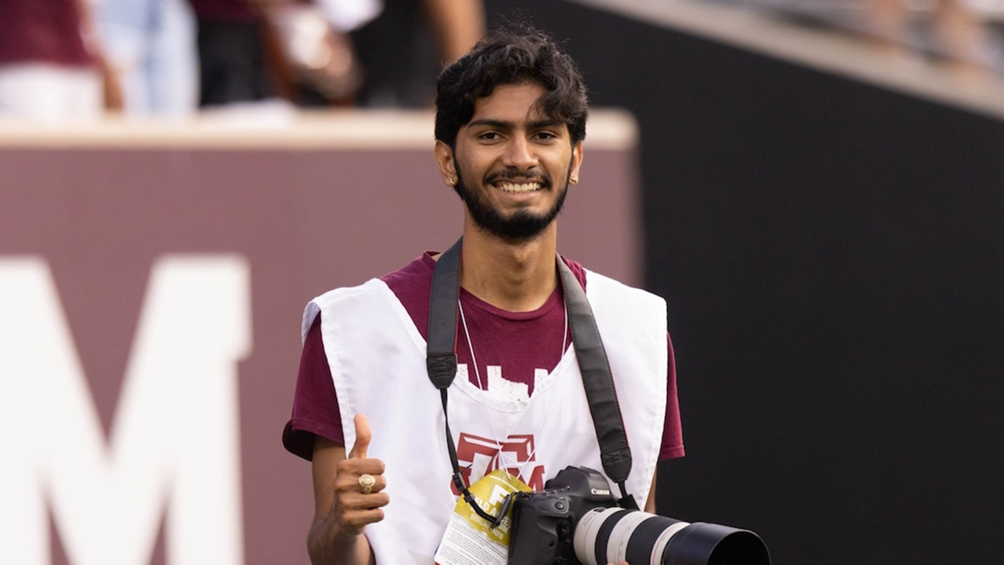 A man with a telephoto lens camera at a sports event. 
