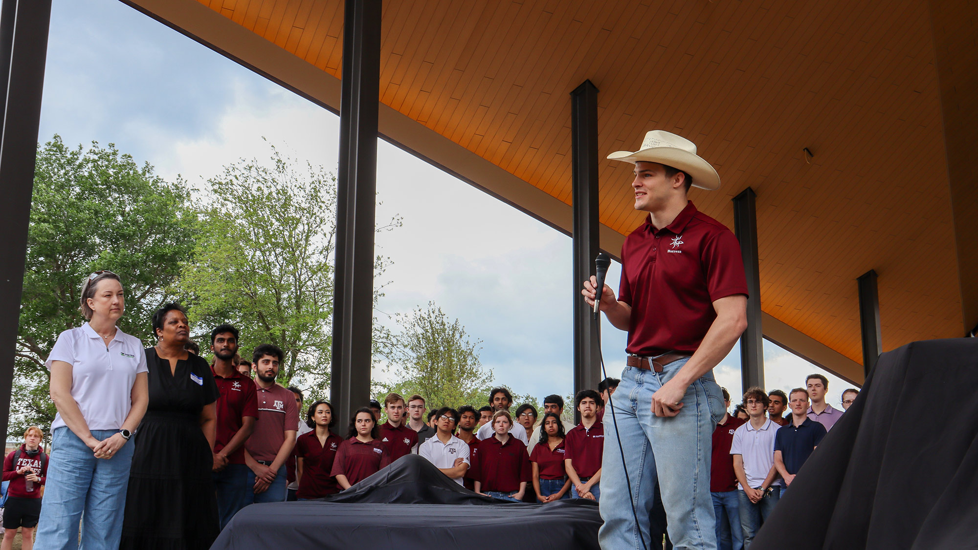 A man with a microphone addresses a group of students.