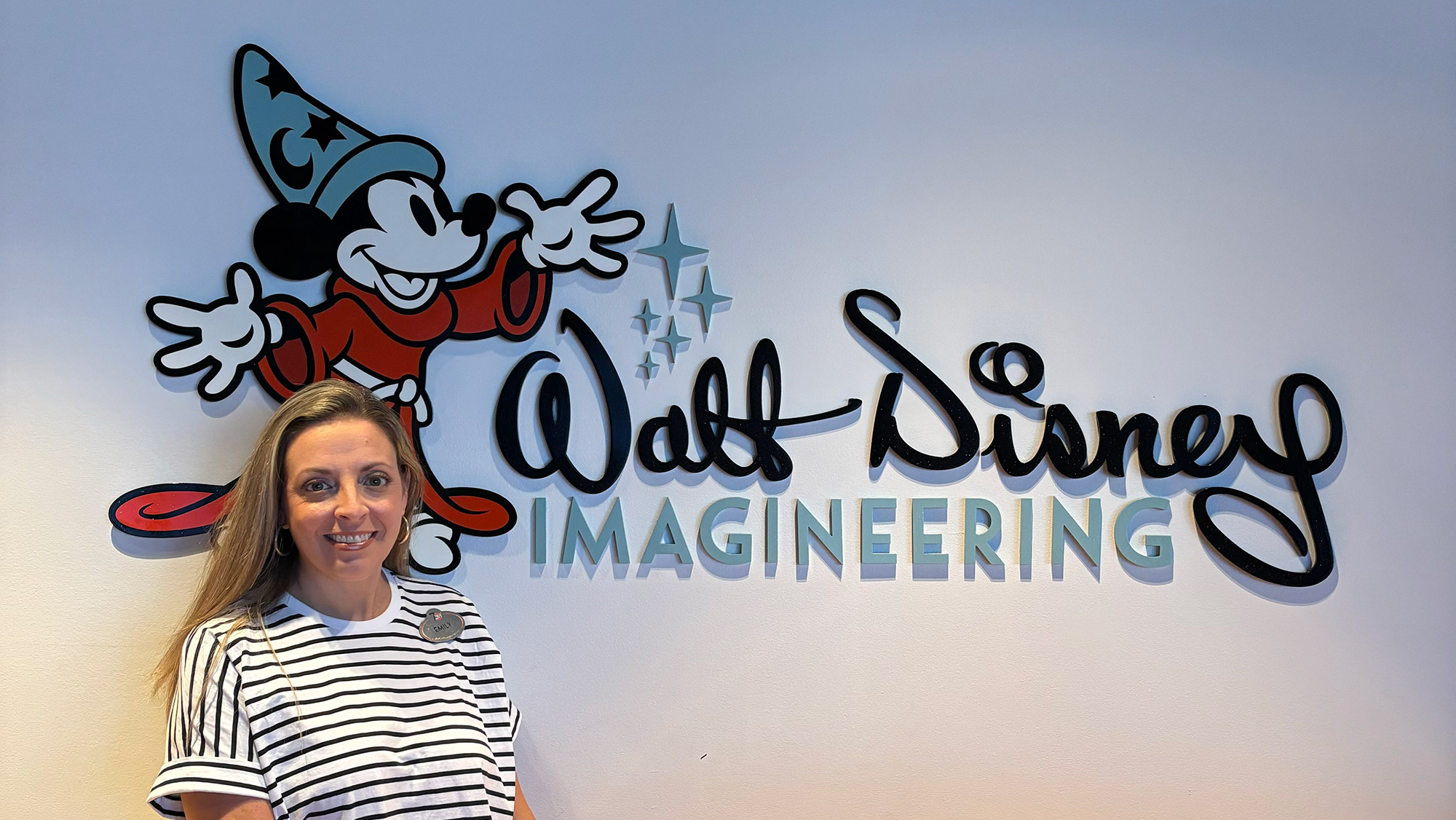 Woman posing in front of wall that says "Walt Disney Imagineering."