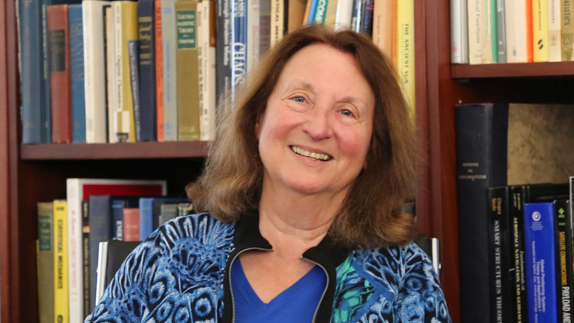 A photo of a person in front of a bookcase.