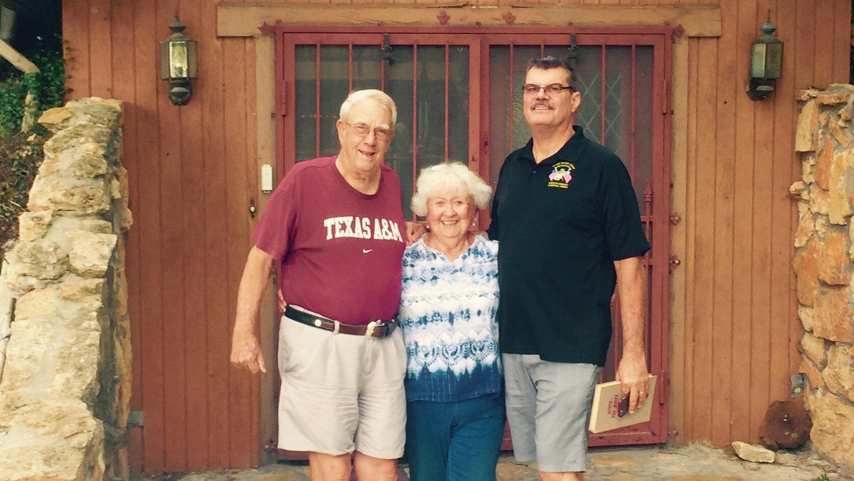 Two men and a woman in front of a house.