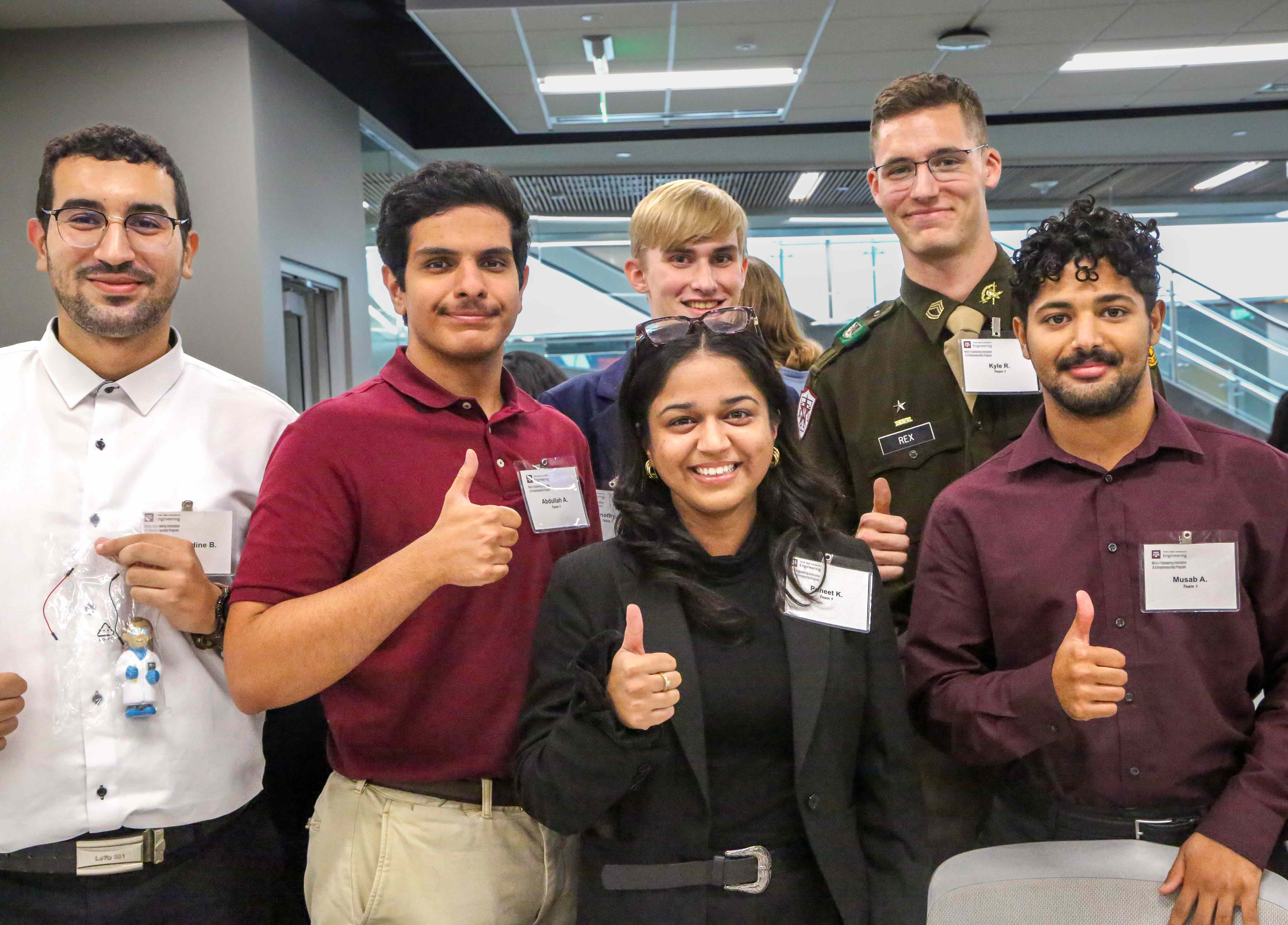 Six students smile and give a thumbs-up