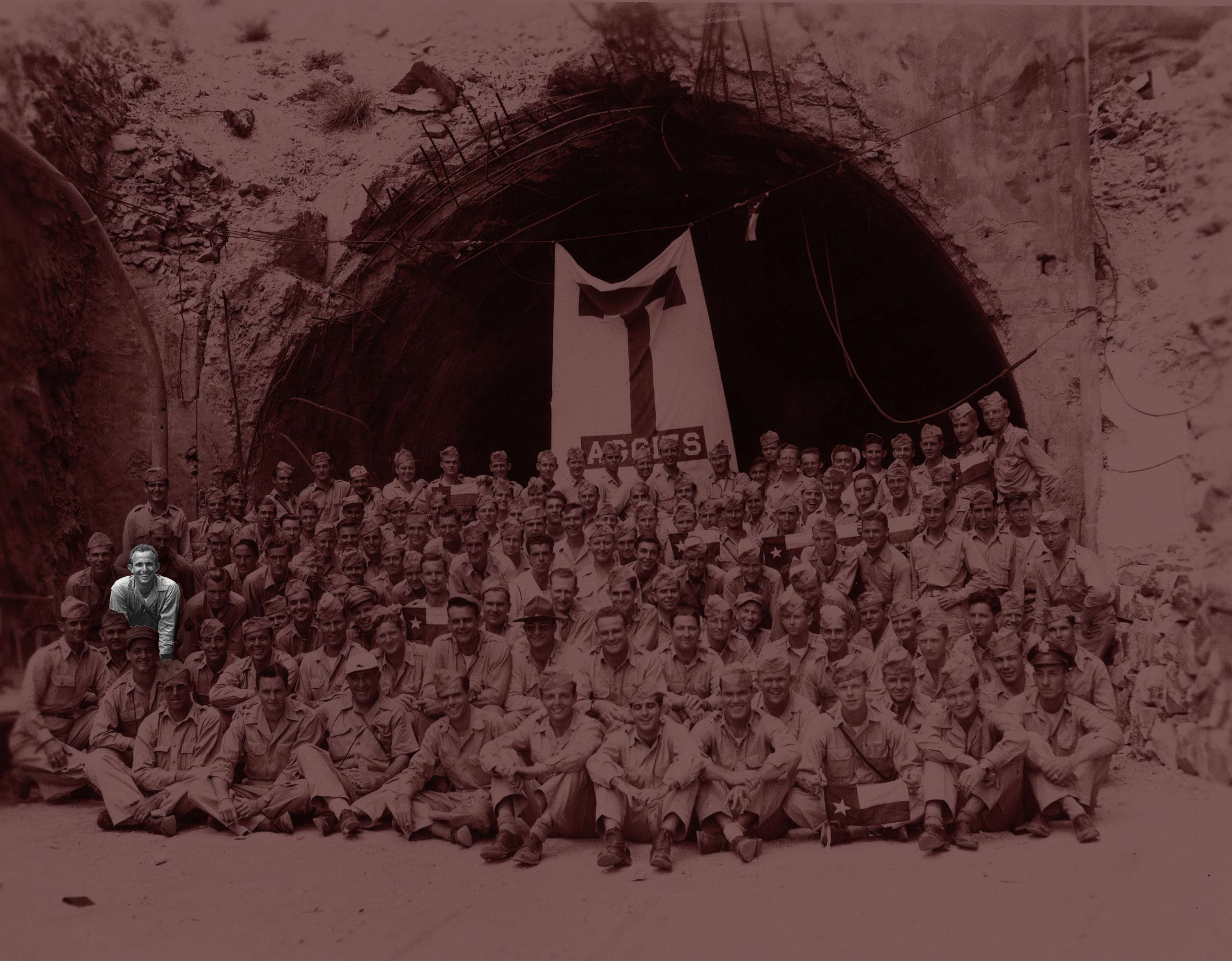 Group of men in the military posing in front of a tunnel entrance with tools and equipment.