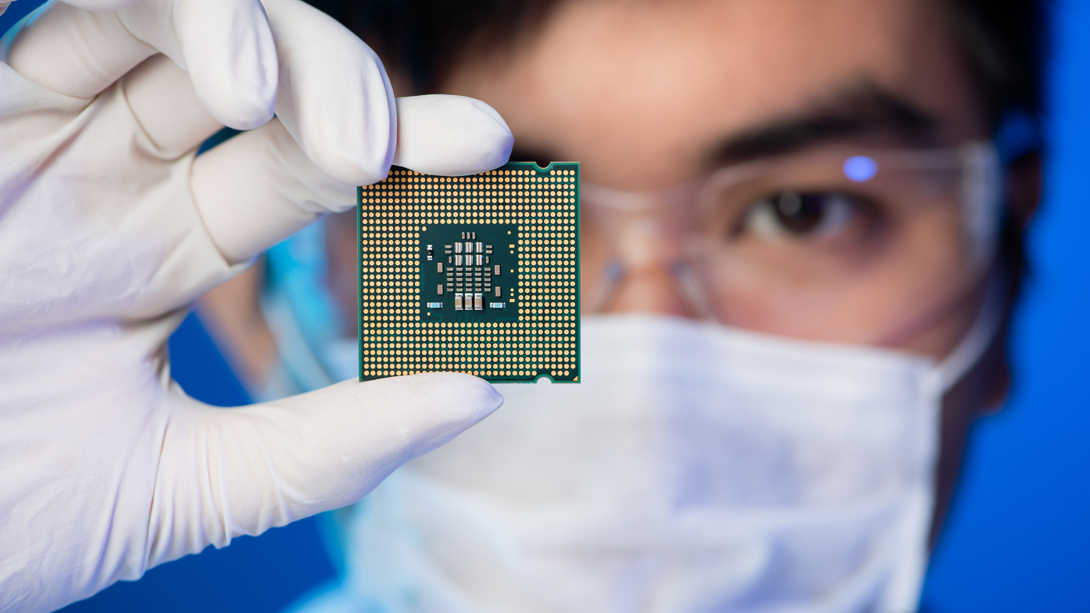 Scientist holding an electronic chip in front of his face.