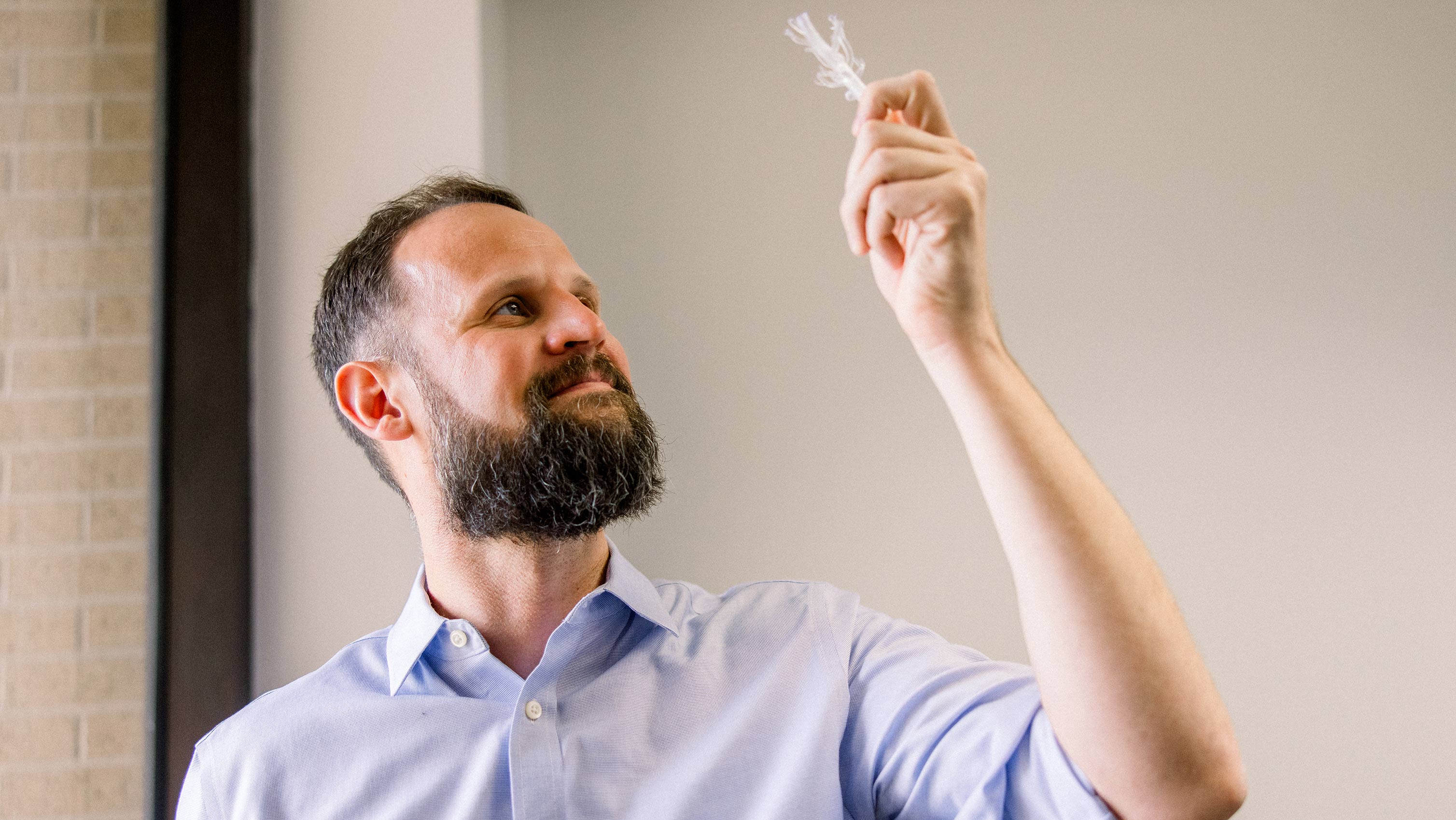 A man looking up at a clear model of a vascular system and smiling.