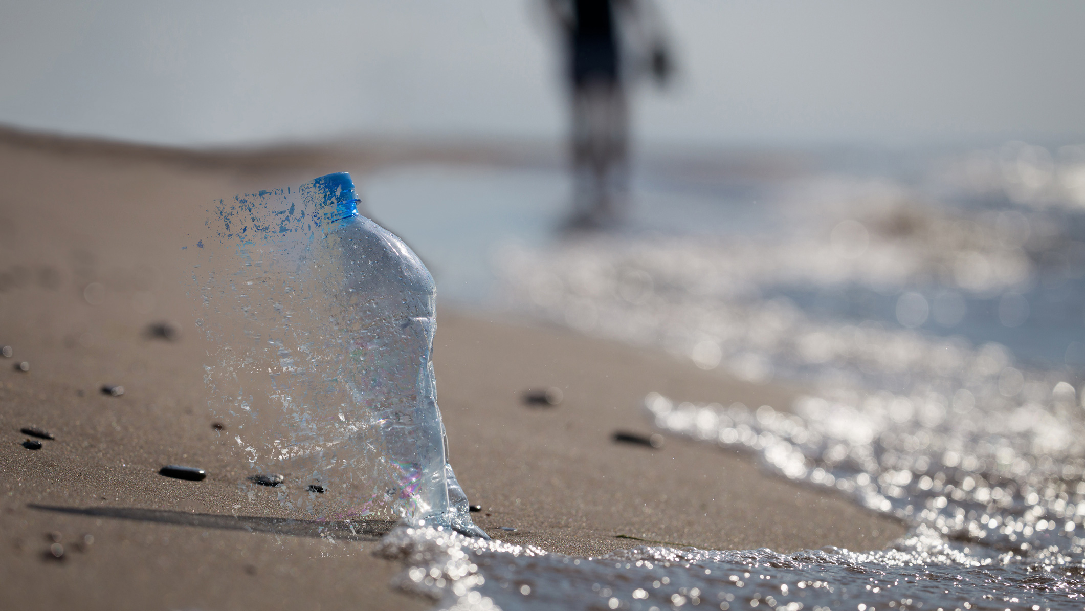 A plastic bottle dissolving into water at a beach