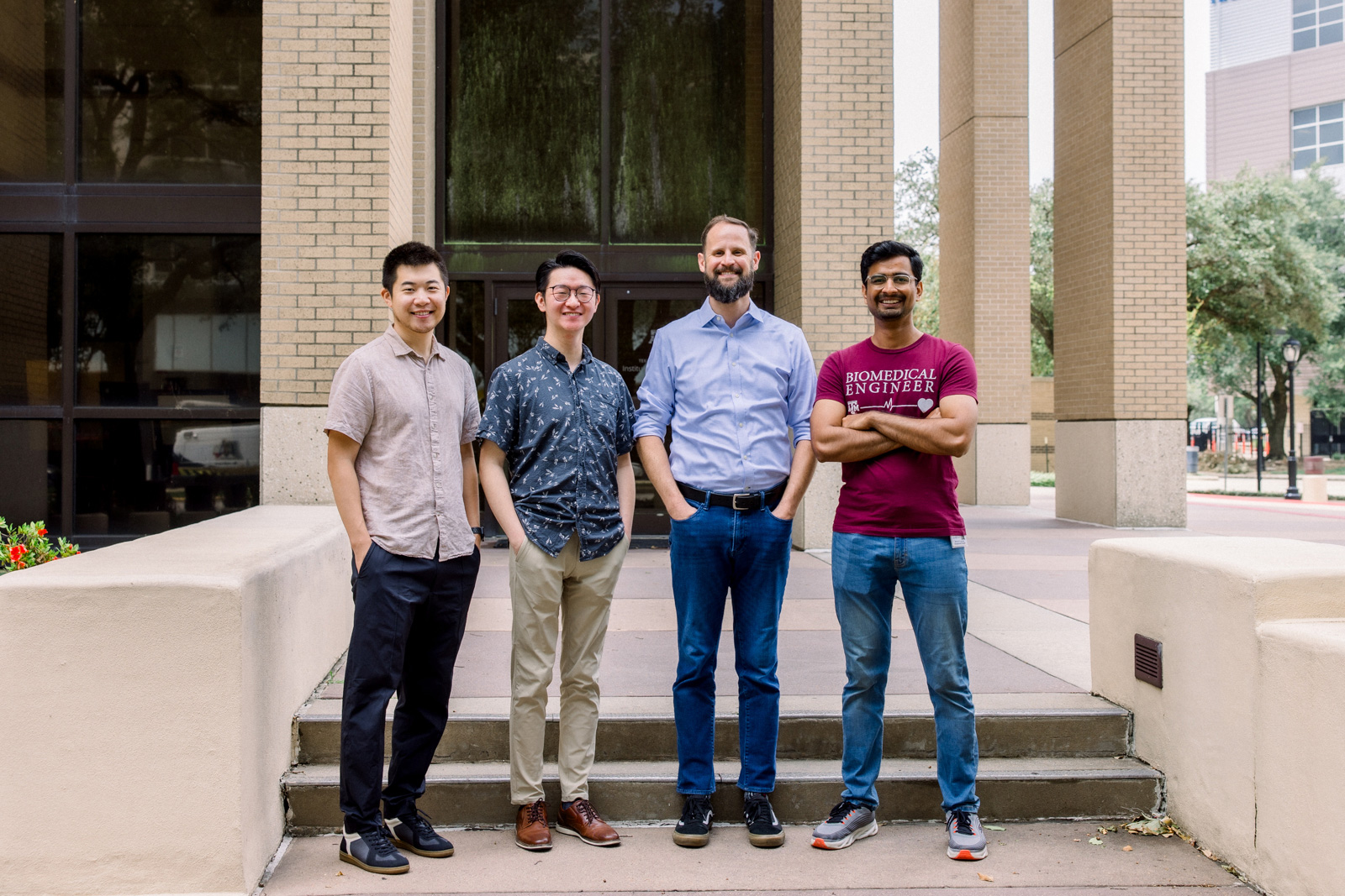 A group of researchers standing on the steps of a building, smiling. 