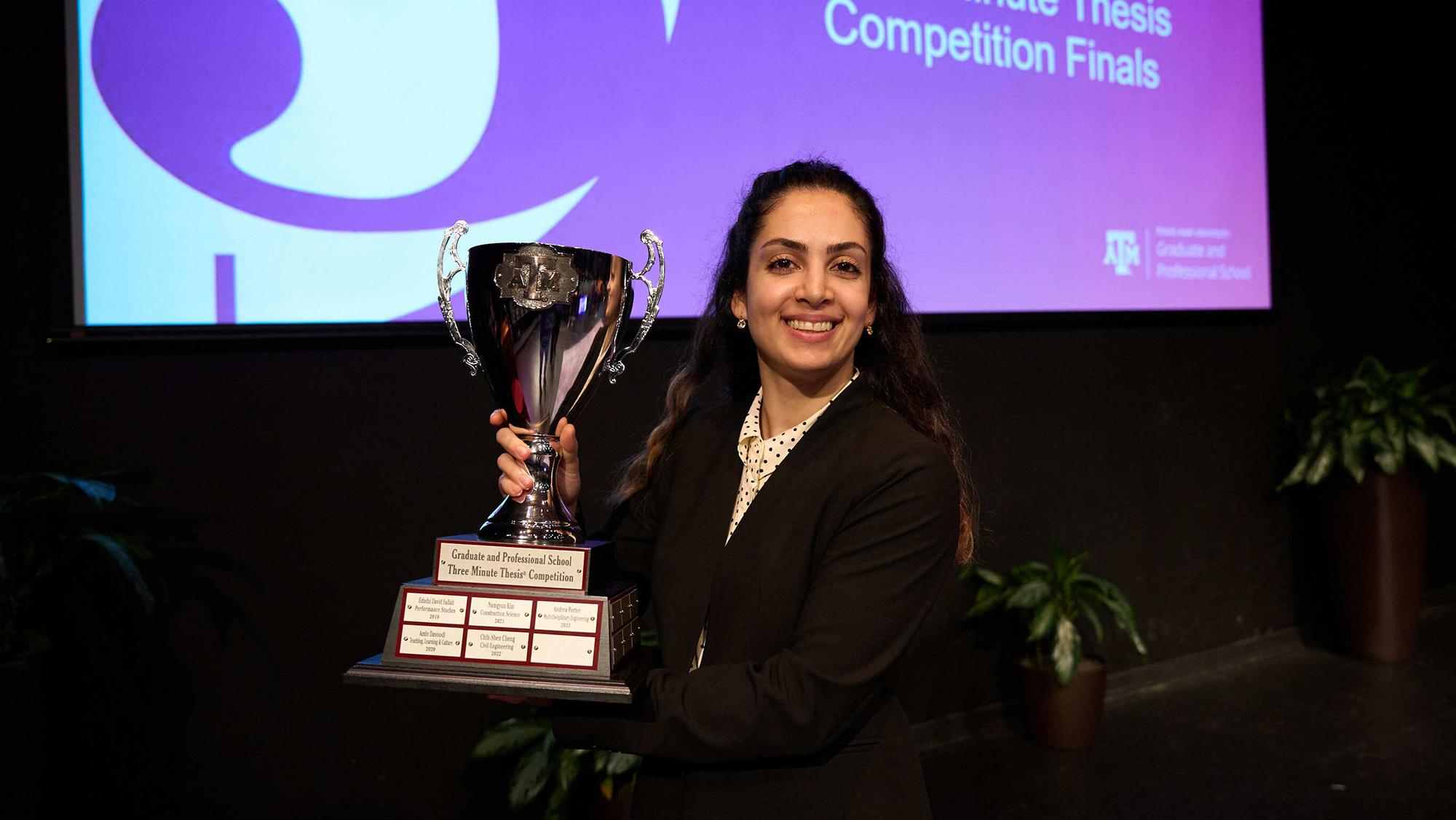 A woman holds a trophy.