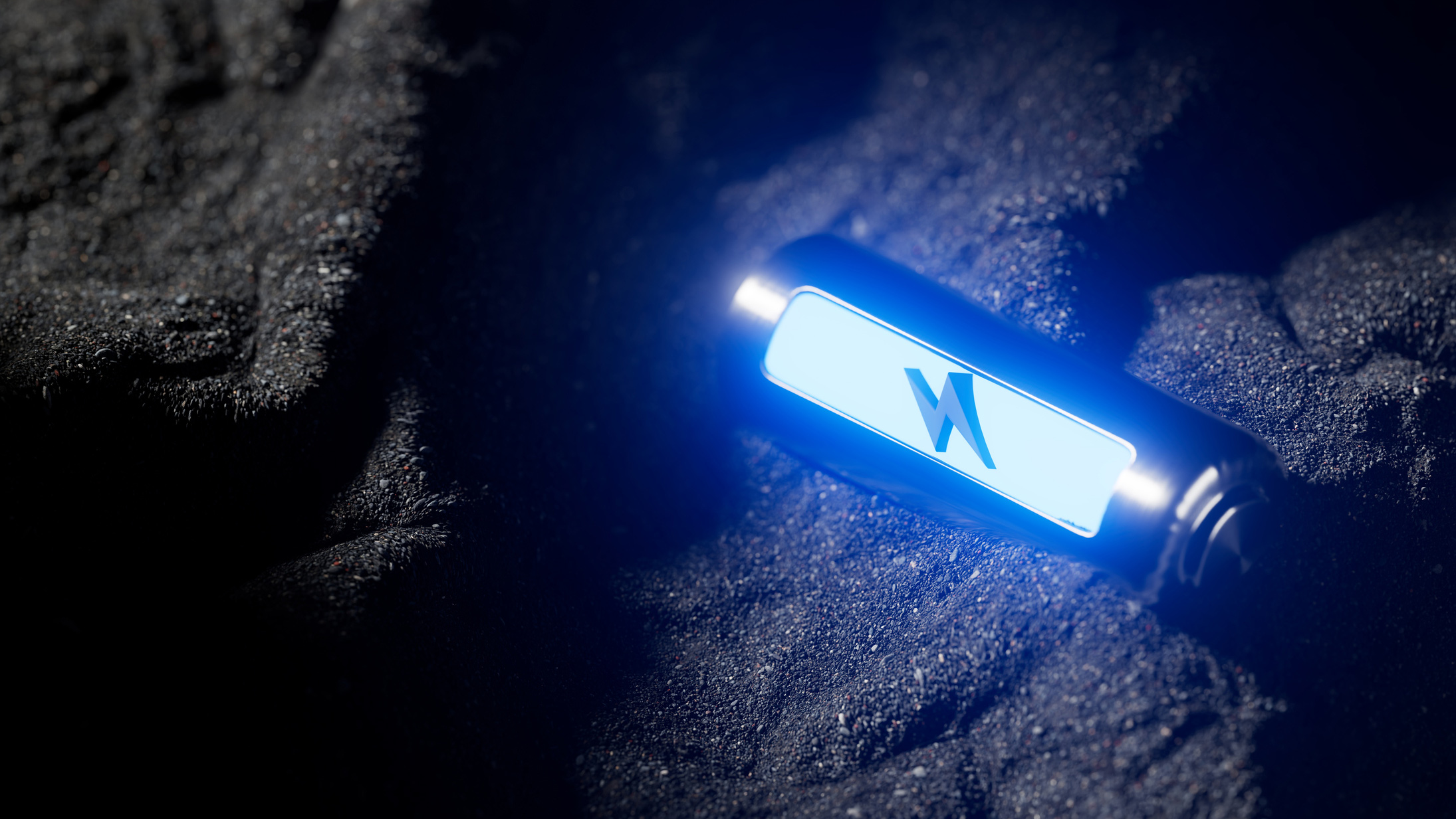 A small metallic device with a blue illuminated logo rests on a dark, textured surface.