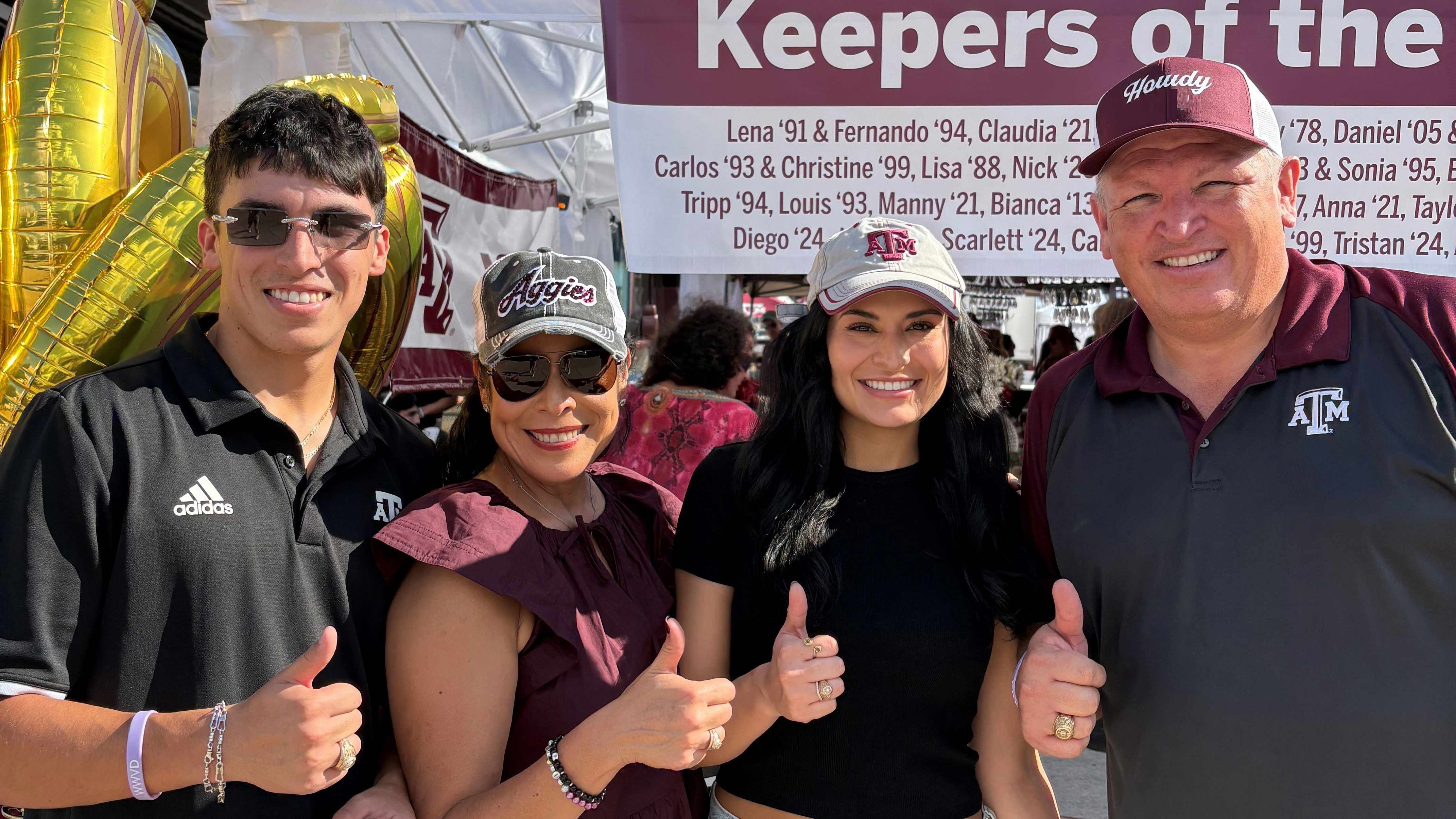 A family of four giving the thumbs up.