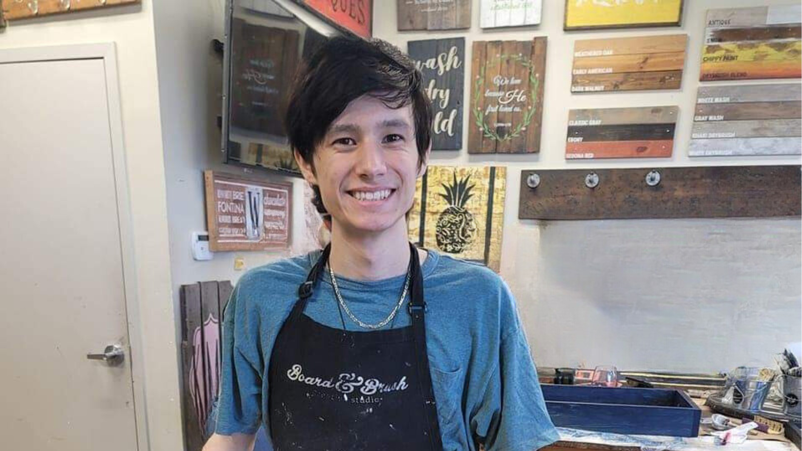 A young man holding a wooden sign.