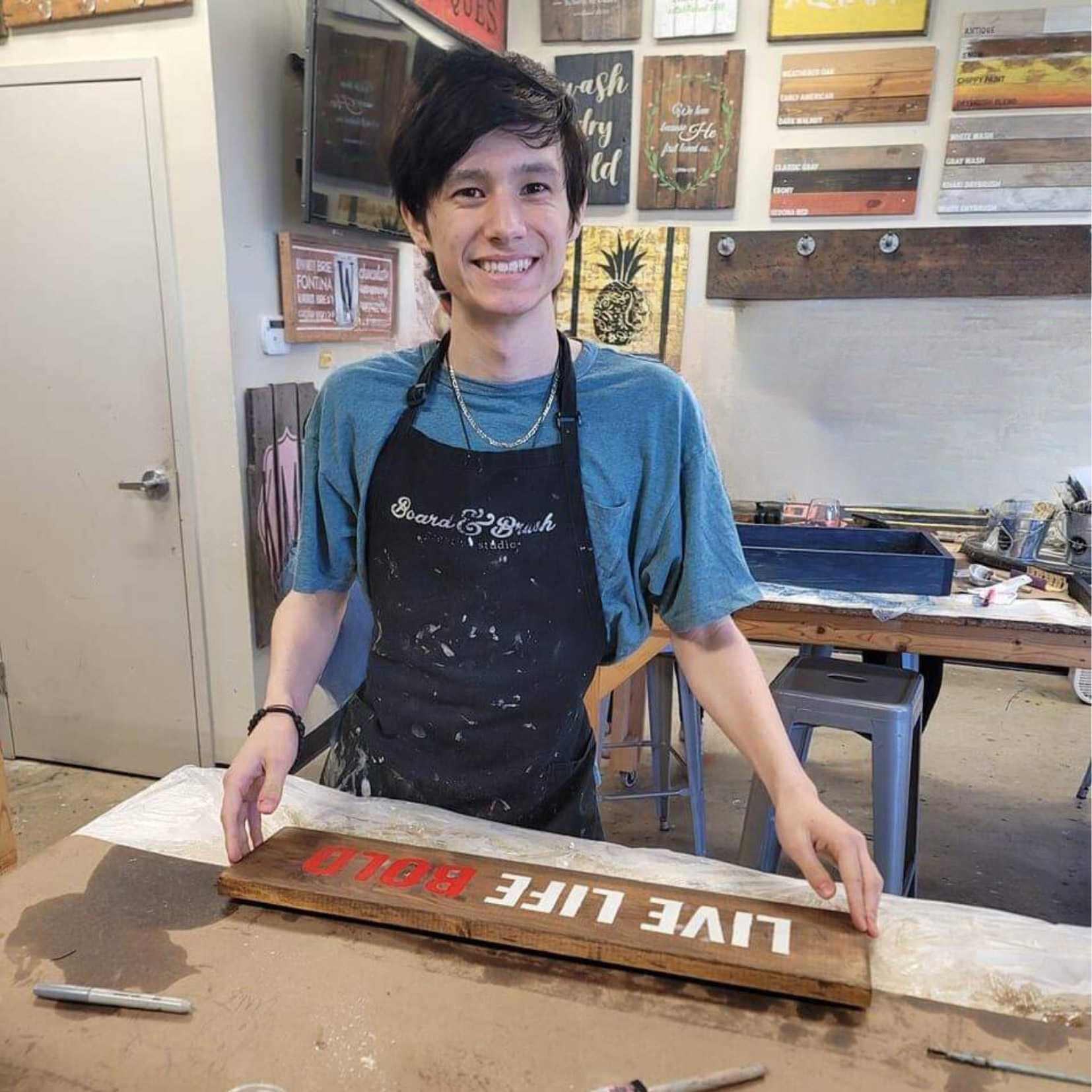 A young man holding a wooden sign.