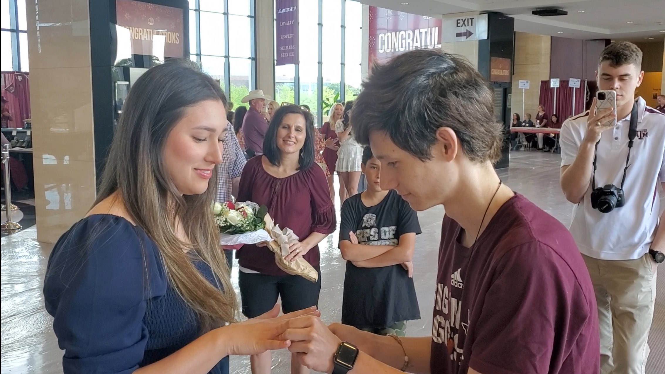 A young man putting a ring on a woman’s finger.