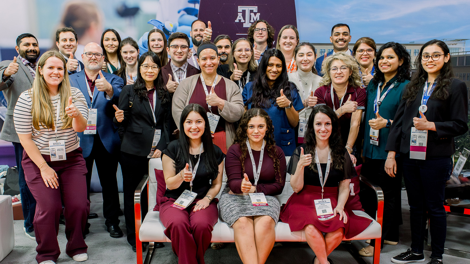 A group of people at a conference booth posing for a photo.