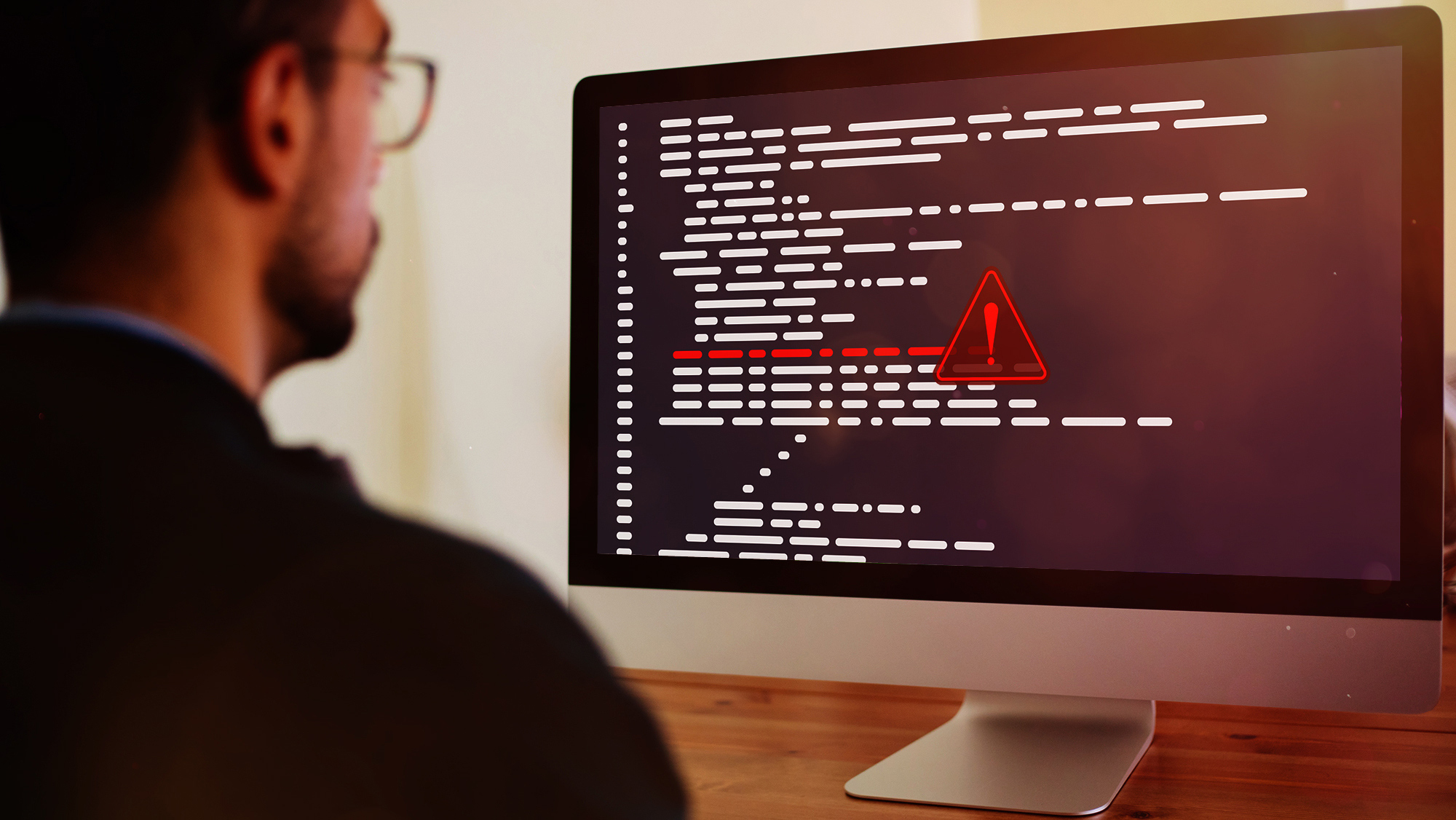 A person looking at a computer screen with a red warning sign. 