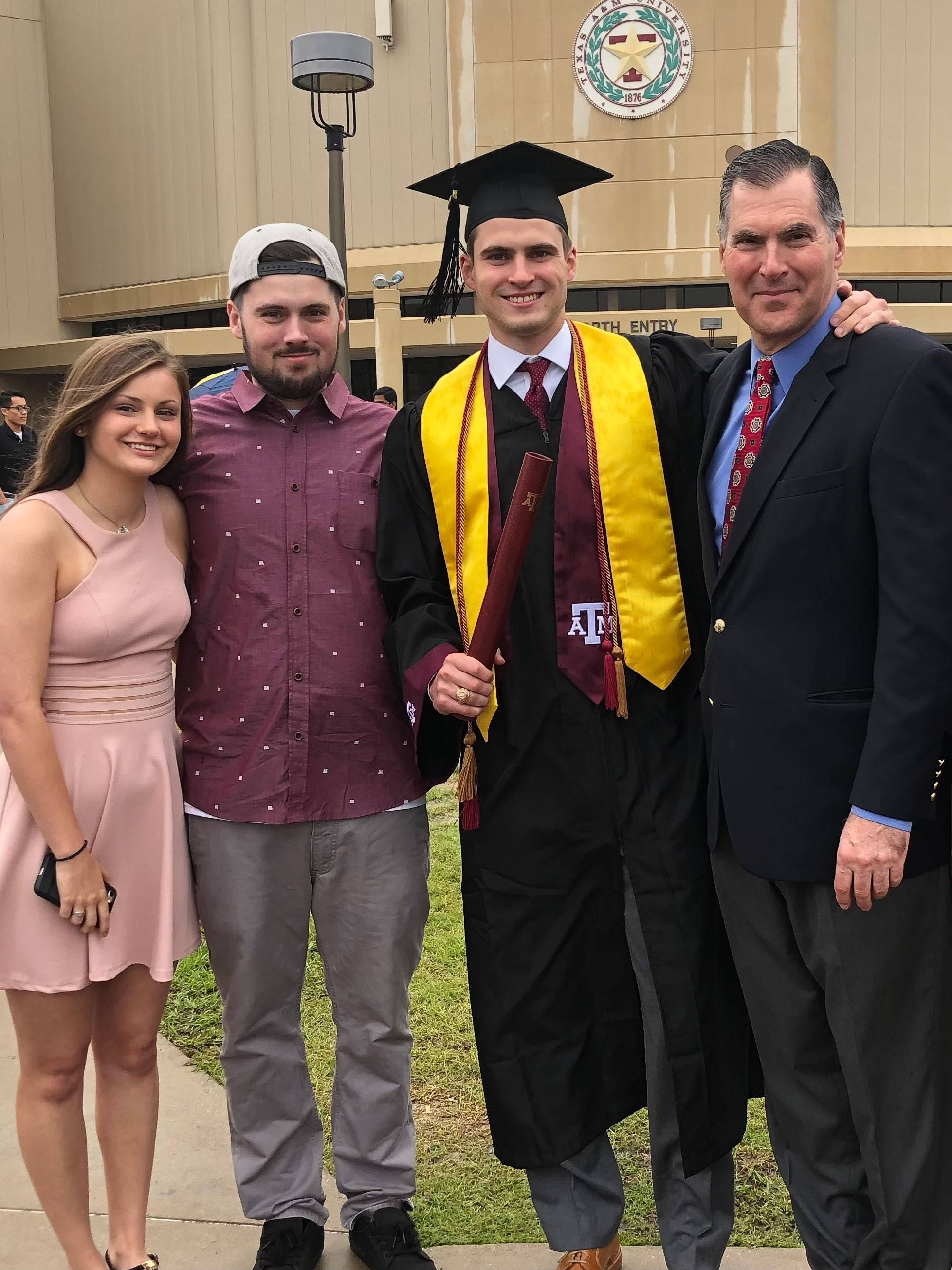 A group of four people pose for a graduation photo. 