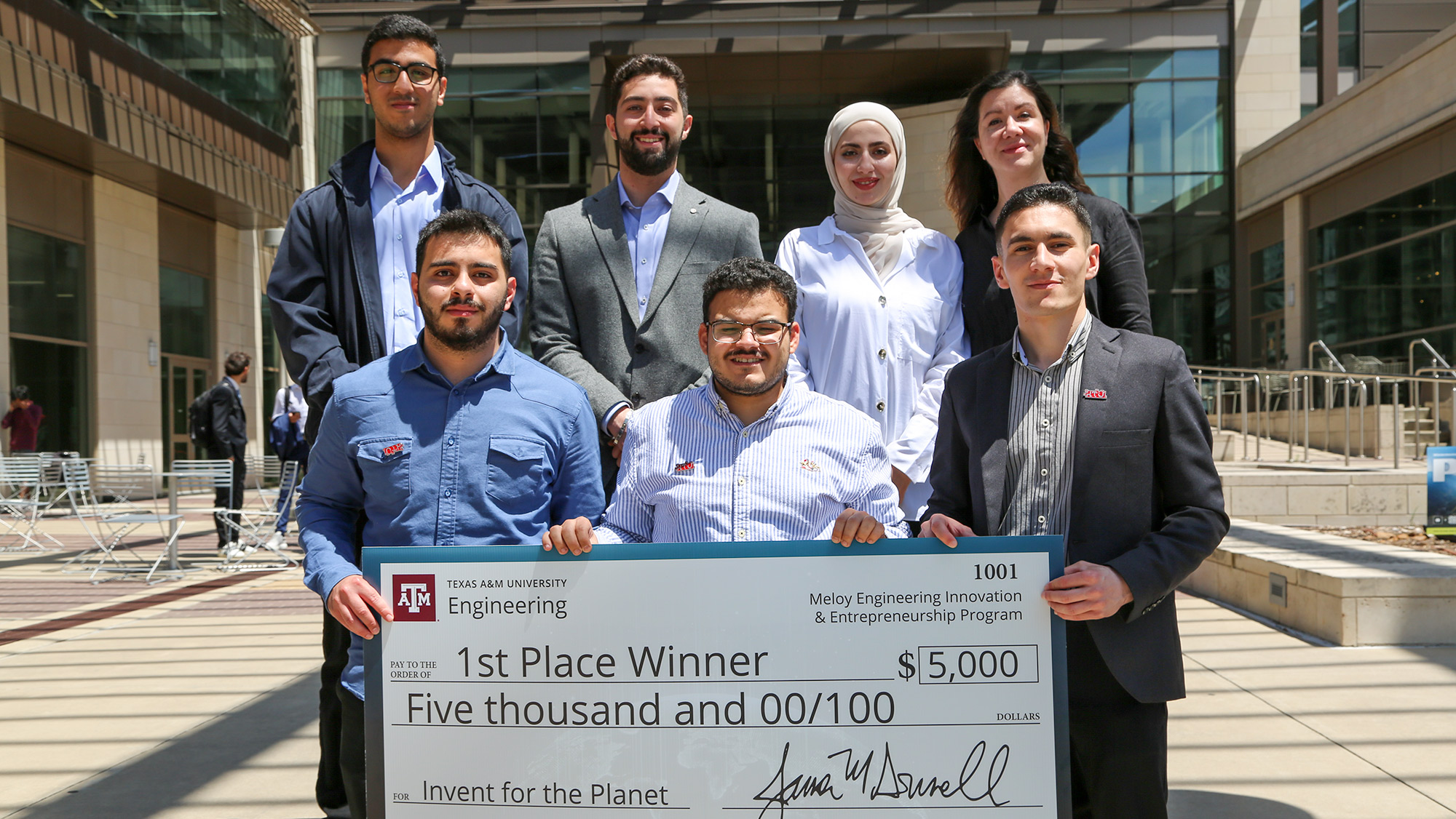 A group of people holding a large check for $5,000.