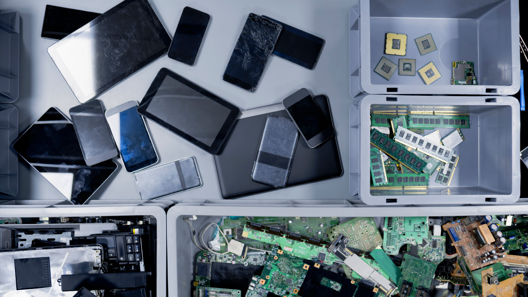A photo of separate bins with discarded smartphones, tablets, and circuit boards.