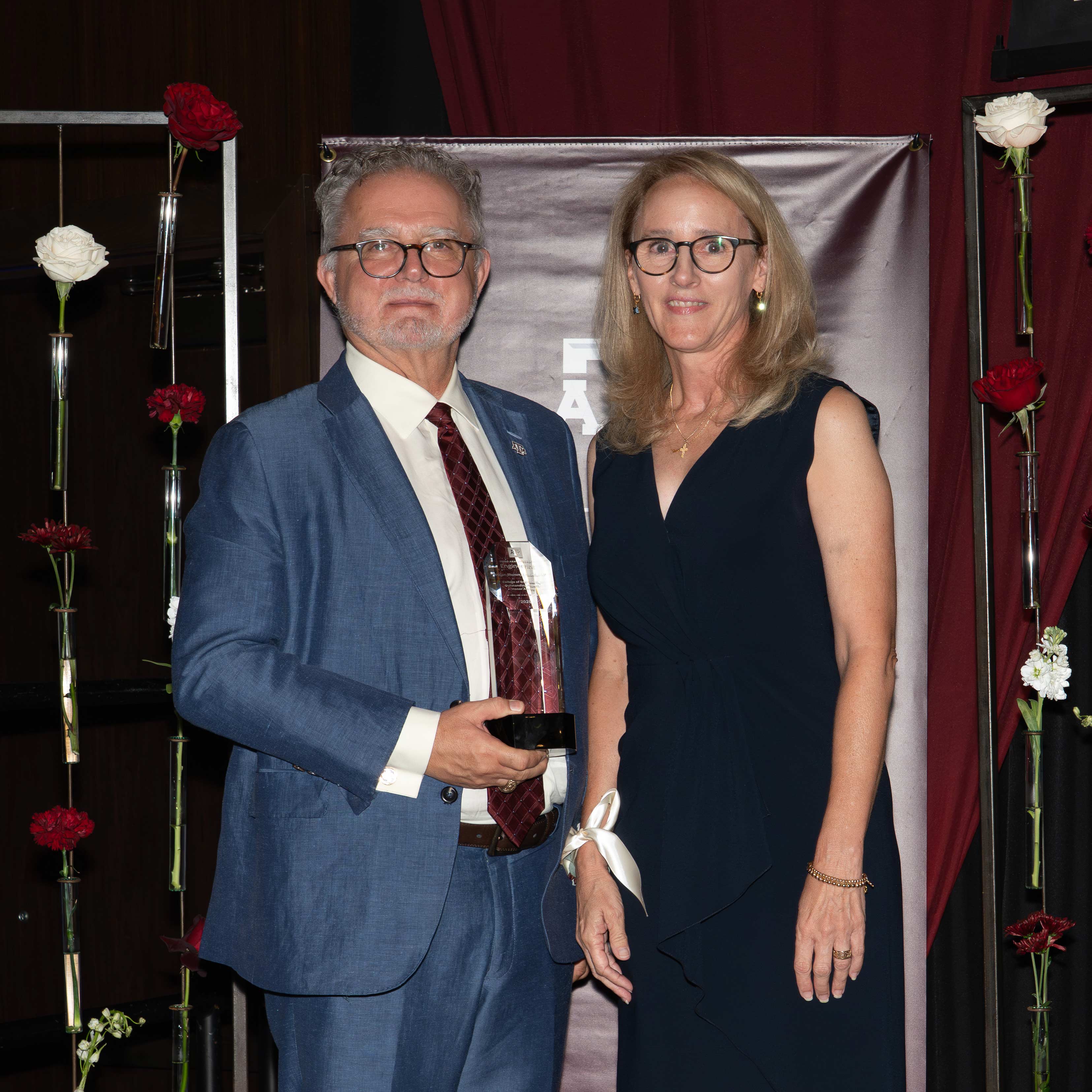 A man and woman pose with an award.