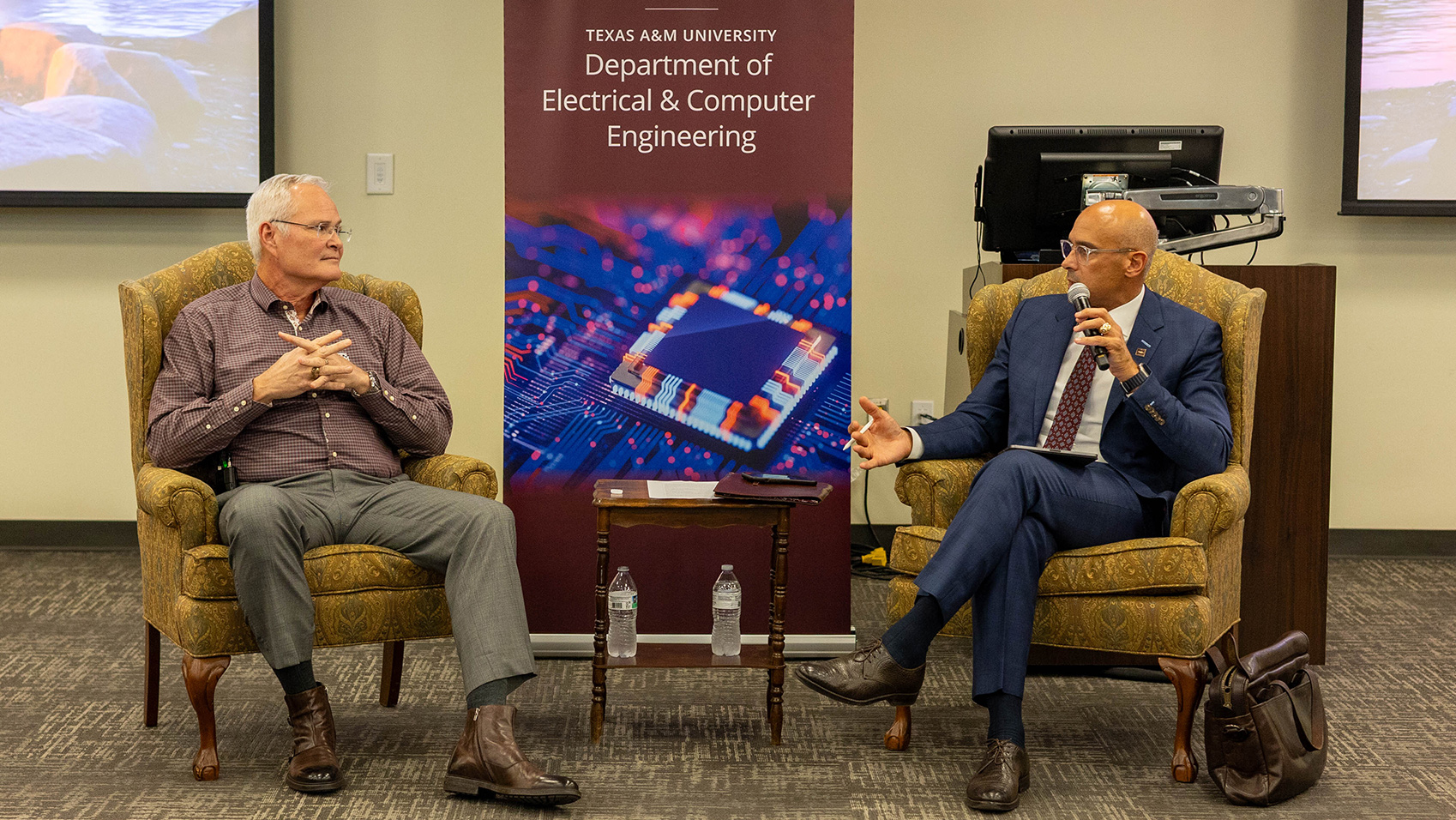 Two men speaking as they sit in chairs.