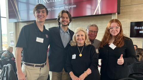 The Gastinger's stand with three students.