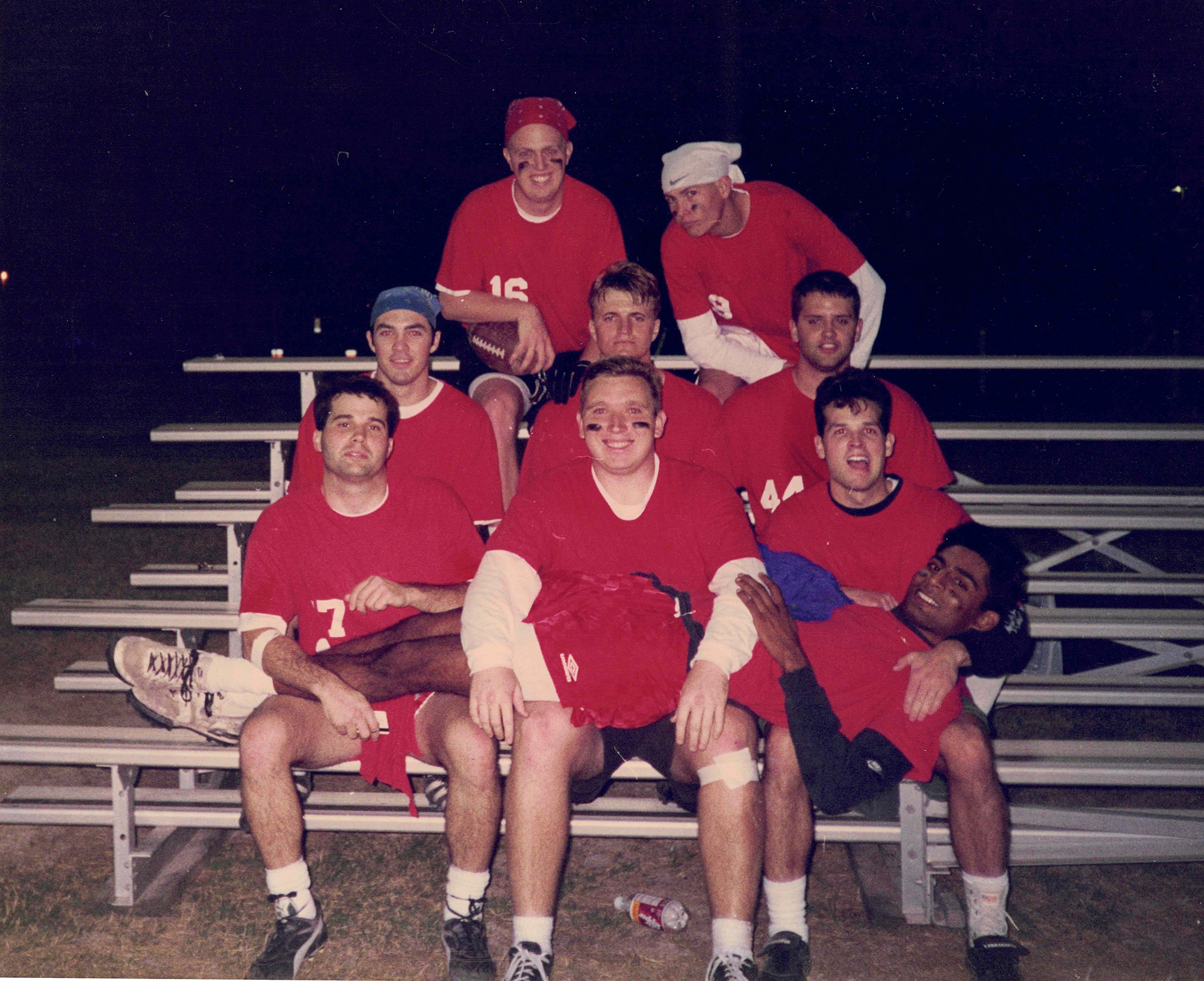 A group of men wearing jerseys sitting in bleacher stands. 