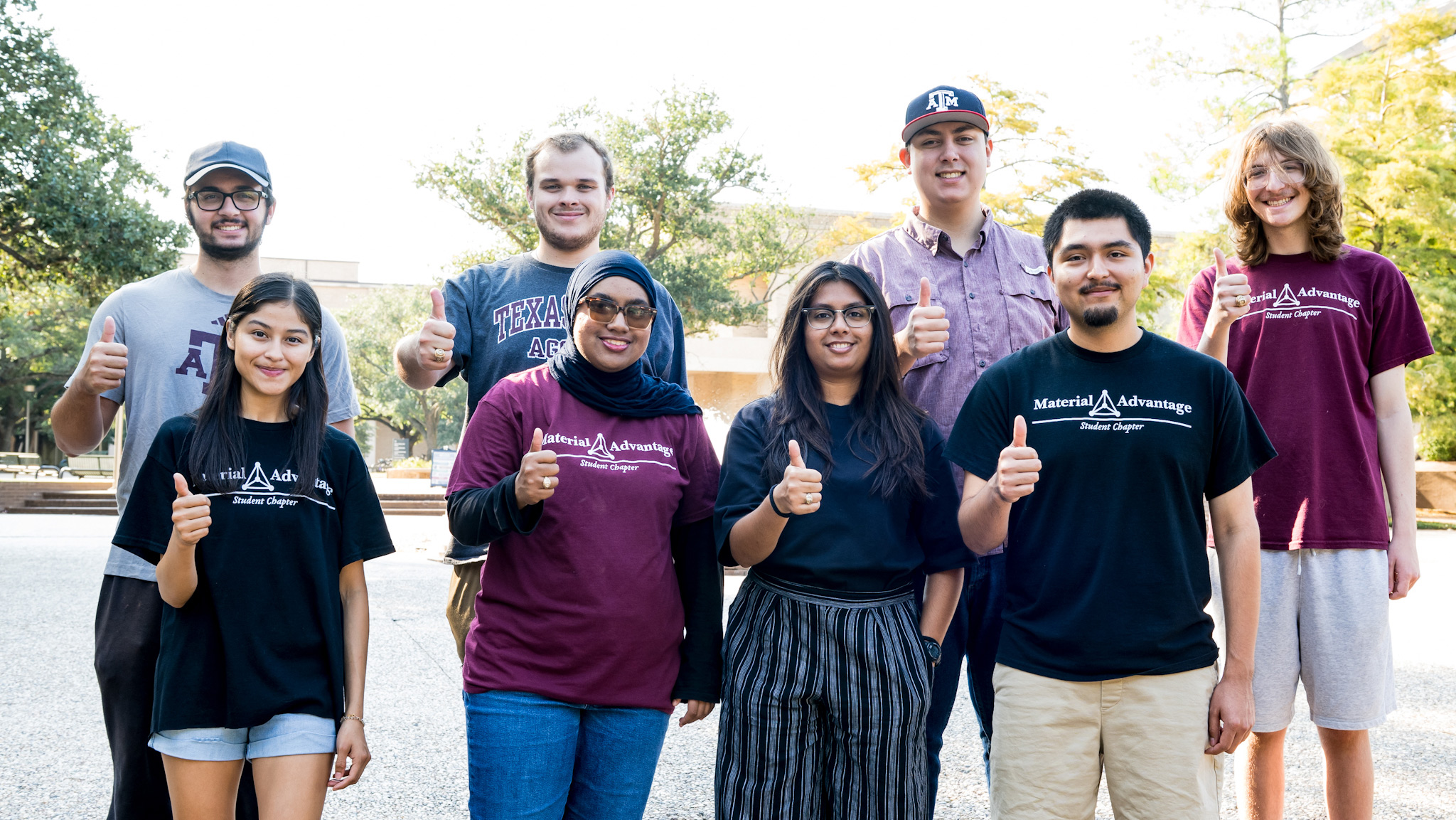 A group of eight Texas A&M University students from the Material Advantage Student Chapter stand outdoors smiling and giving a thumbs-up.