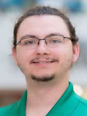 Joseph Rios in a green collared polo shirt wearing glasses