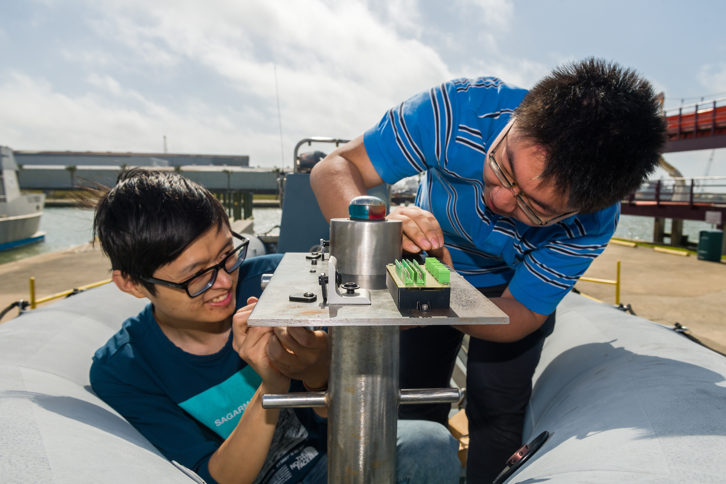 Two students bend over an experiment in a docked boat. 