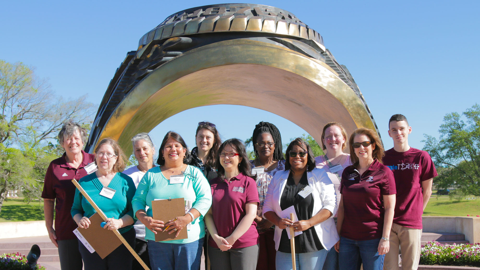 Group of staff and students in front of Aggie ring statue