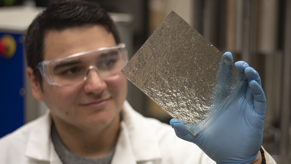 graduate student inspecting a clear-resin 3-D printed model of rock fractures