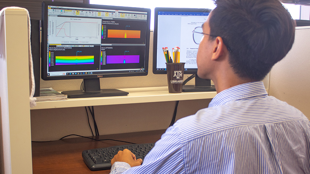 seated male petroleum engineering student at Texas A&amp;M University looking at a computer monitor showing four graphs depicting the injection status, temperature, strain and rock displacement a carbon dioxide sample created in a well during a simulation experiment